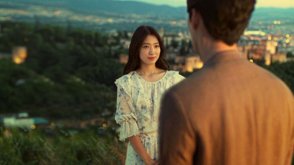 Park Shin-hye observa um personagem em frente à paisagem de Granada, na Espanha, em cena do dorama Memories of the Alhambra.